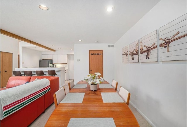 carpeted dining space featuring beamed ceiling