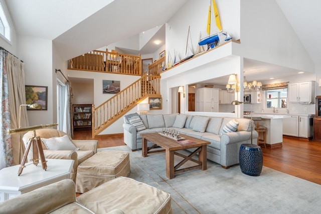 living room featuring high vaulted ceiling, plenty of natural light, sink, and light hardwood / wood-style floors