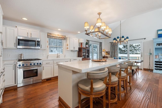 kitchen with appliances with stainless steel finishes, decorative backsplash, a chandelier, and hanging light fixtures