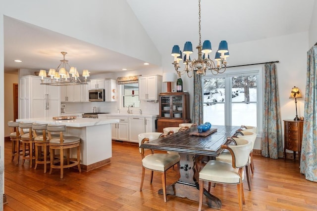 dining space featuring high vaulted ceiling, light wood-type flooring, and a chandelier