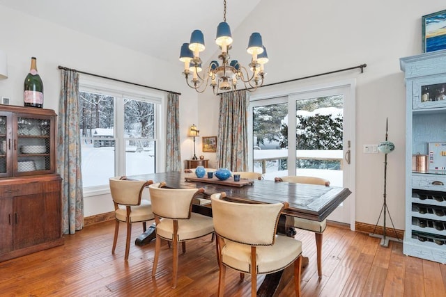 dining area featuring vaulted ceiling, an inviting chandelier, and hardwood / wood-style floors