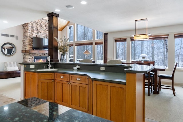 kitchen featuring sink, hanging light fixtures, a center island with sink, and light carpet