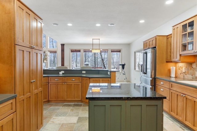 kitchen featuring decorative light fixtures, a center island, high end refrigerator, and dark stone counters