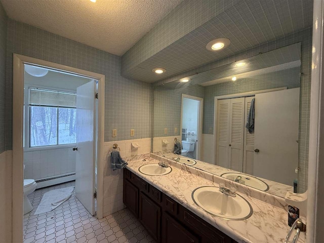 bathroom featuring a baseboard radiator, tile patterned flooring, vanity, tile walls, and toilet