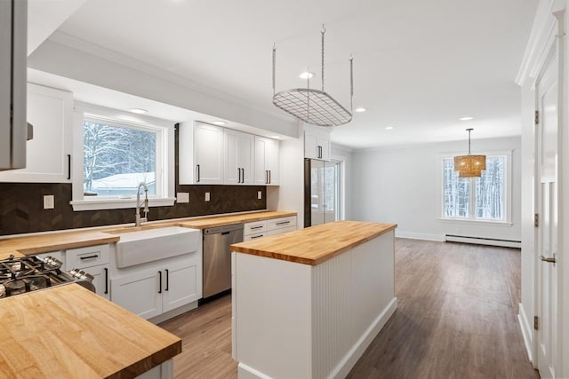 kitchen with decorative light fixtures, white cabinets, wooden counters, and a kitchen island