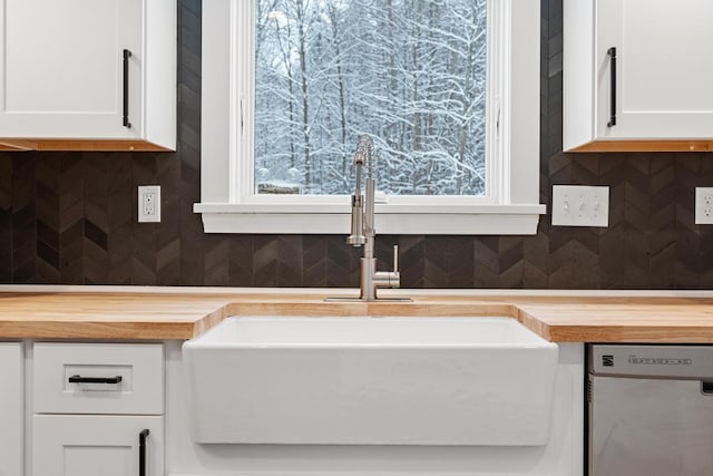 interior details with sink, white cabinetry, stainless steel dishwasher, and tasteful backsplash