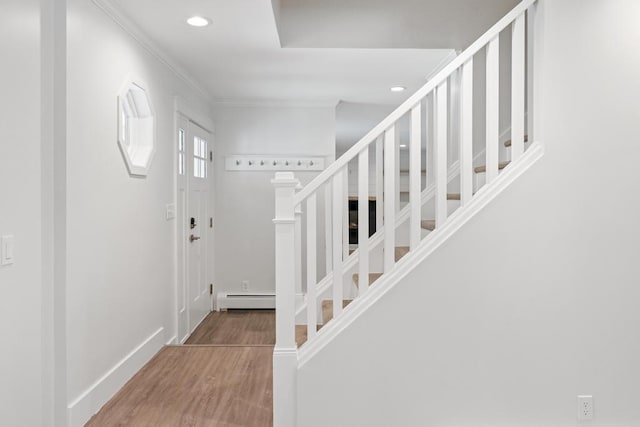 foyer entrance with hardwood / wood-style flooring, ornamental molding, and a baseboard radiator