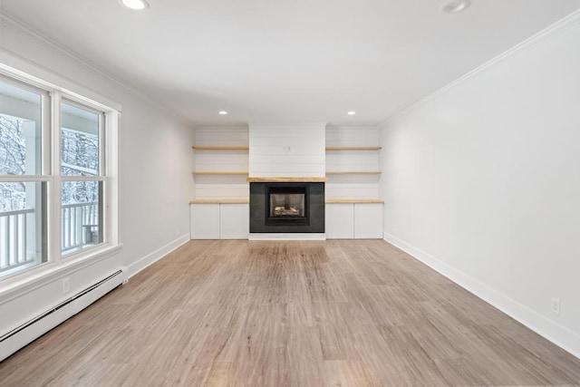 unfurnished living room with light wood-type flooring, a large fireplace, crown molding, and a baseboard radiator