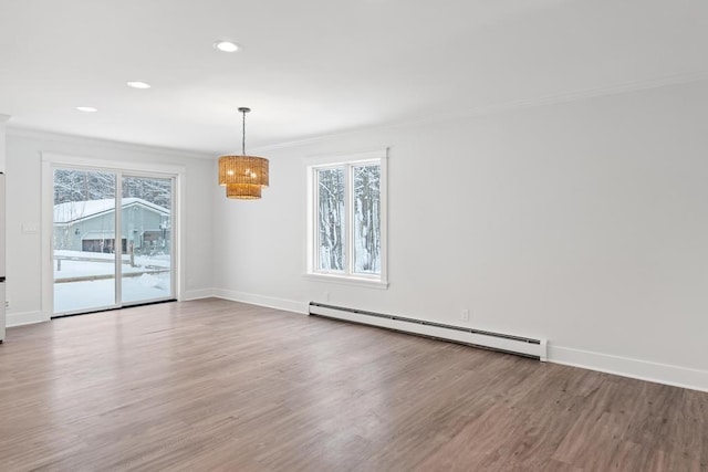 empty room with a baseboard heating unit, crown molding, and hardwood / wood-style flooring