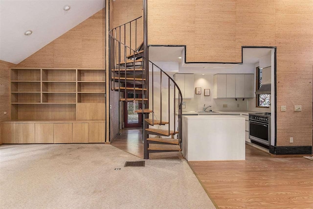 stairway featuring high vaulted ceiling and sink