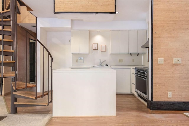 kitchen featuring extractor fan, wood walls, range, white cabinets, and sink