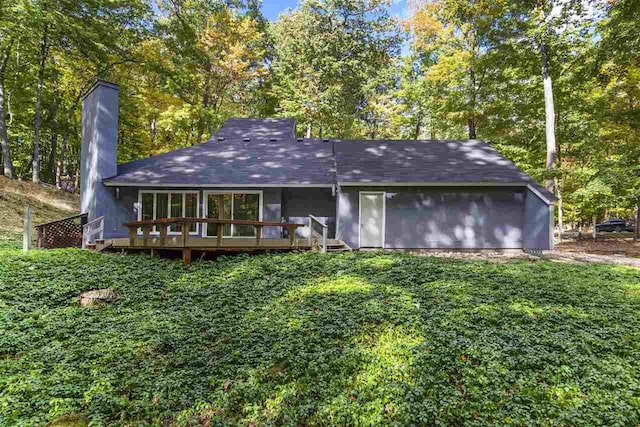 rear view of property featuring a deck and a yard