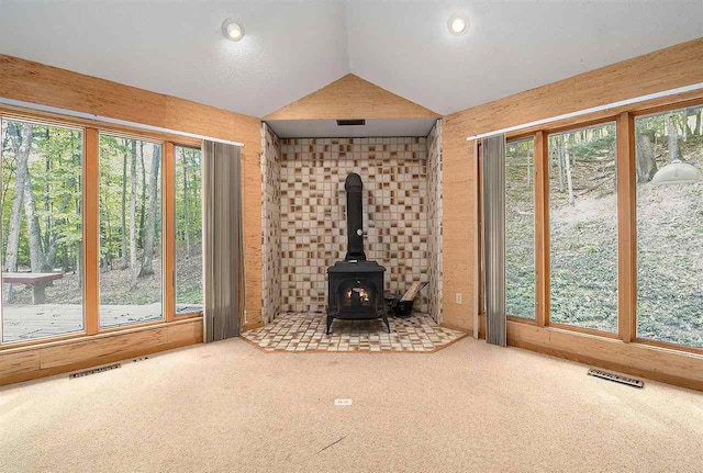 unfurnished living room with carpet, lofted ceiling, and a wood stove