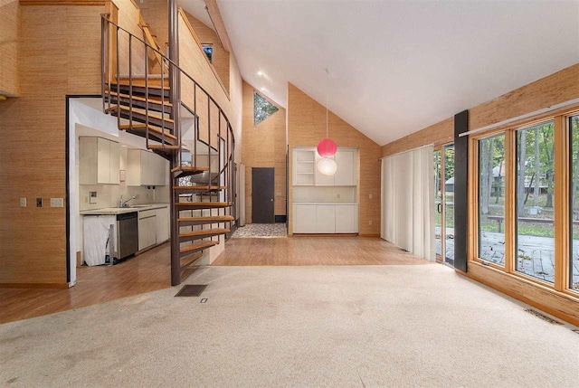 unfurnished living room with high vaulted ceiling, light colored carpet, and sink