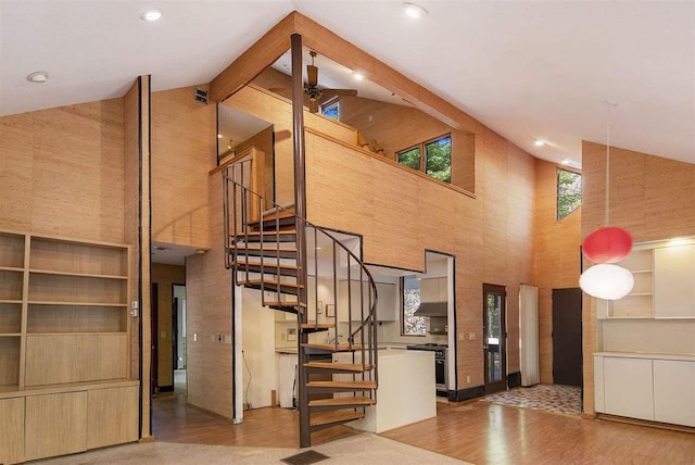 stairs featuring high vaulted ceiling, wood-type flooring, beamed ceiling, and wooden walls