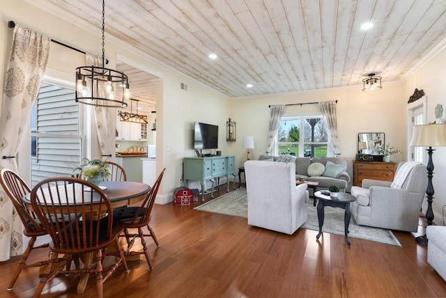 living room with hardwood / wood-style floors, crown molding, a chandelier, and wooden ceiling