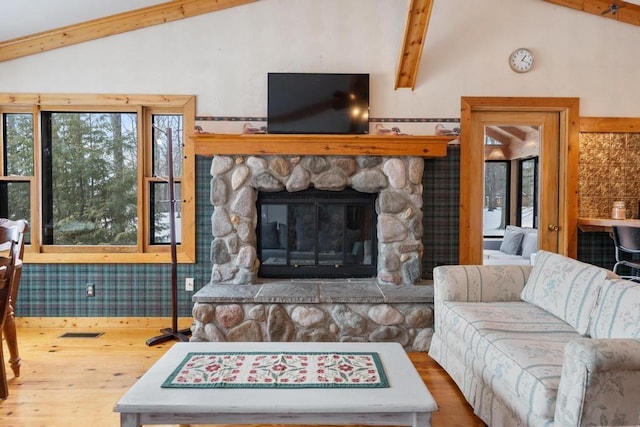 living room with wood-type flooring, lofted ceiling, and a stone fireplace