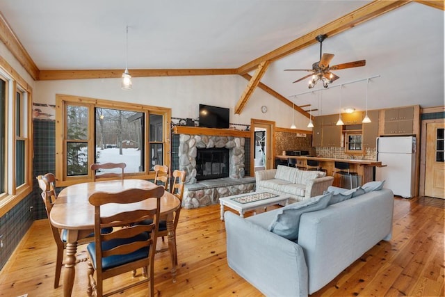 living room with light wood-type flooring, ceiling fan, lofted ceiling, and a fireplace