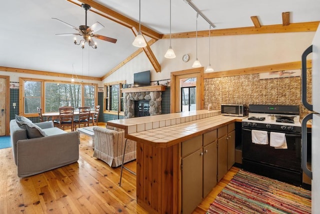 kitchen featuring vaulted ceiling with beams, tile countertops, range with gas cooktop, and kitchen peninsula