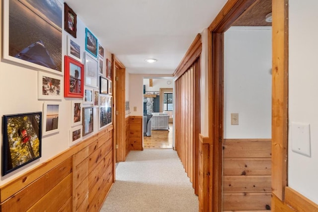 hall featuring light carpet and wood walls