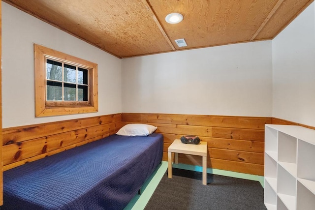 carpeted bedroom featuring wooden ceiling, ornamental molding, and wood walls