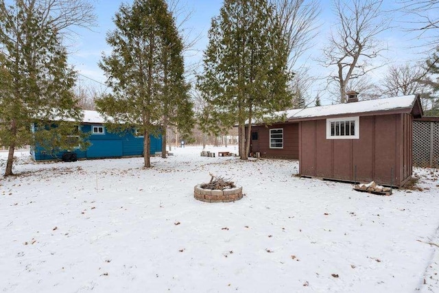 yard layered in snow featuring a storage shed and a fire pit