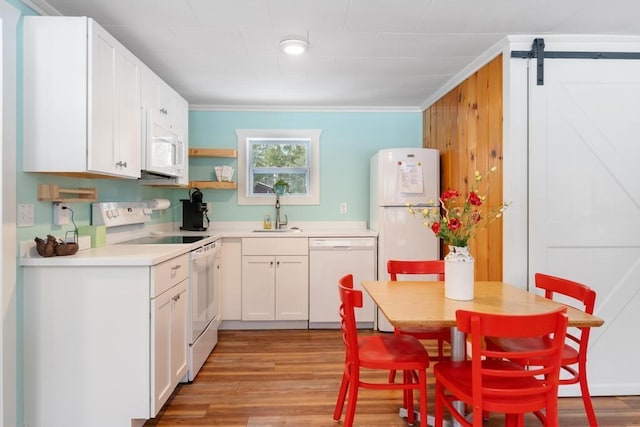 kitchen featuring white appliances, white cabinets, sink, ornamental molding, and a barn door