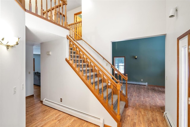 stairs featuring hardwood / wood-style floors, a towering ceiling, and a baseboard radiator