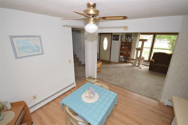 living room featuring ceiling fan, wood-type flooring, a baseboard heating unit, and a textured ceiling