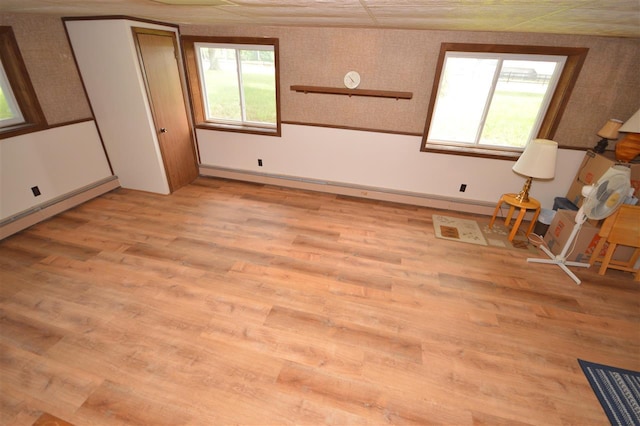 spare room featuring a baseboard heating unit and light hardwood / wood-style flooring