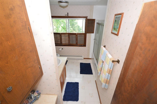 bathroom with walk in shower, vanity, and baseboard heating