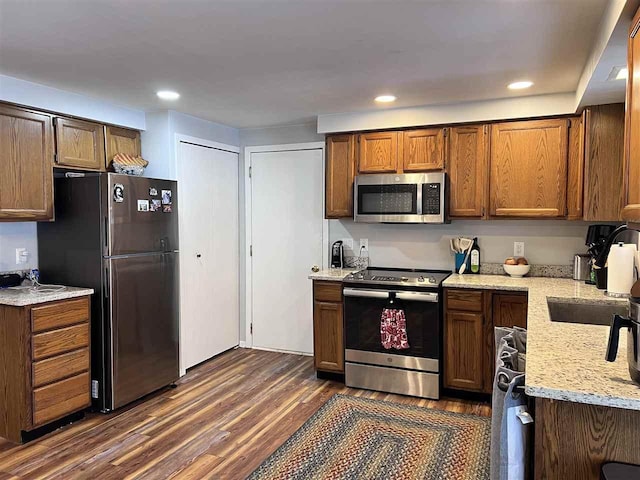 kitchen with light stone counters, dark wood-type flooring, sink, and stainless steel appliances