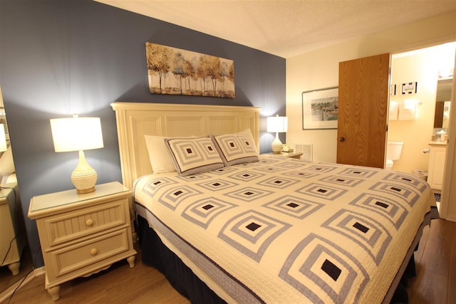 bedroom with ensuite bathroom and hardwood / wood-style flooring