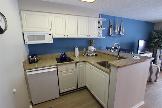 kitchen with white cabinets, dishwashing machine, kitchen peninsula, and dark hardwood / wood-style flooring