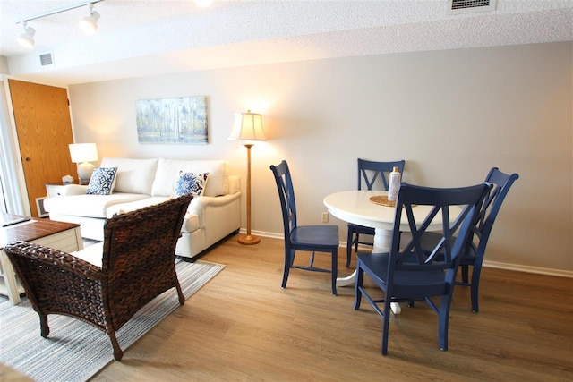 dining room featuring light hardwood / wood-style floors and a textured ceiling