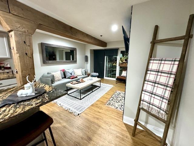 living room featuring beamed ceiling and light hardwood / wood-style floors