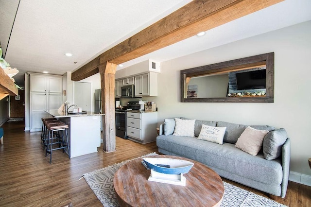 living room featuring dark wood-type flooring, sink, and beam ceiling