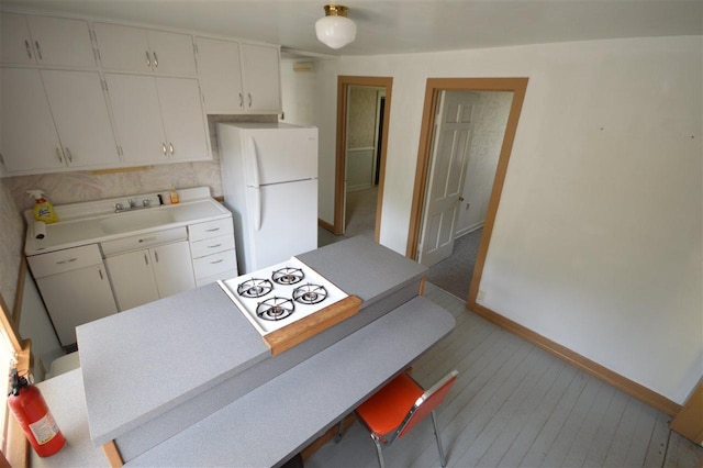 kitchen featuring sink, white refrigerator, and white cabinetry