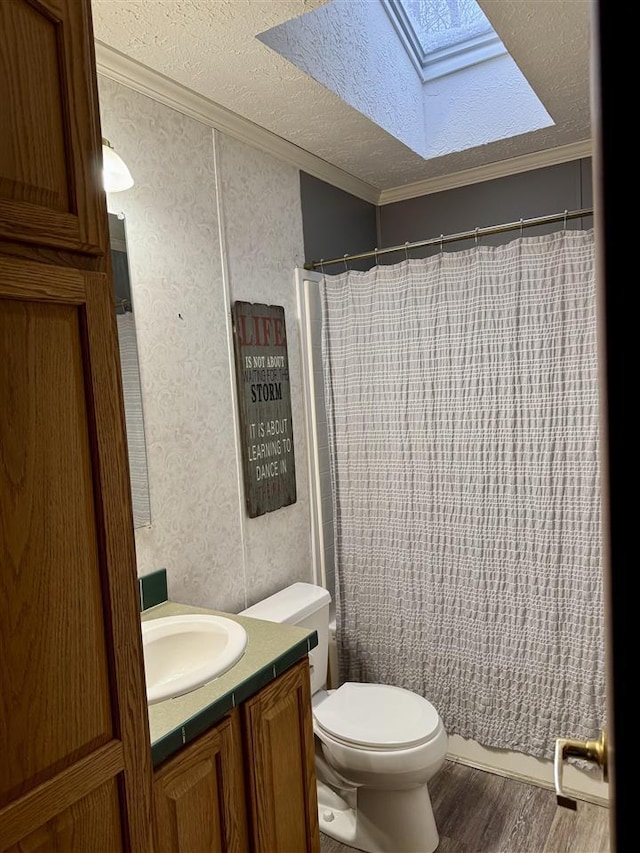 bathroom featuring crown molding, wood-type flooring, a skylight, a textured ceiling, and vanity