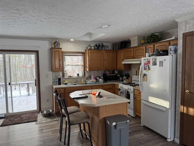 kitchen featuring sink, white appliances, dark hardwood / wood-style floors, and a kitchen island