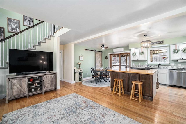 kitchen featuring a barn door, stainless steel dishwasher, a kitchen breakfast bar, white cabinets, and a kitchen island