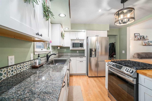 kitchen featuring white cabinets, pendant lighting, appliances with stainless steel finishes, and sink