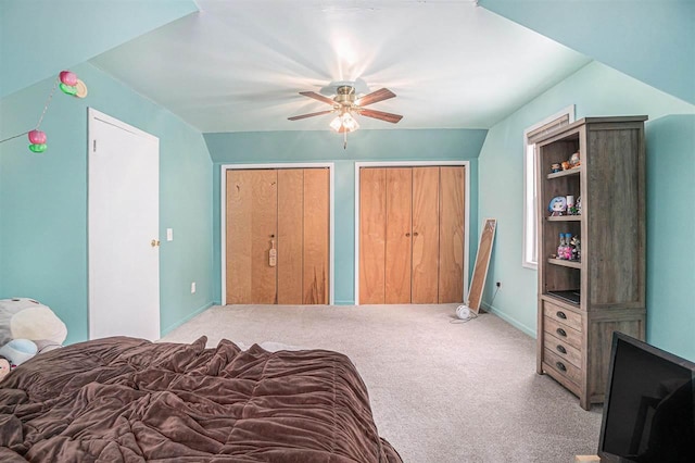 bedroom featuring ceiling fan, light carpet, and multiple closets