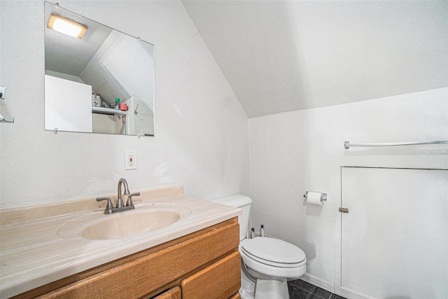 bathroom with tile patterned floors, toilet, vanity, and lofted ceiling