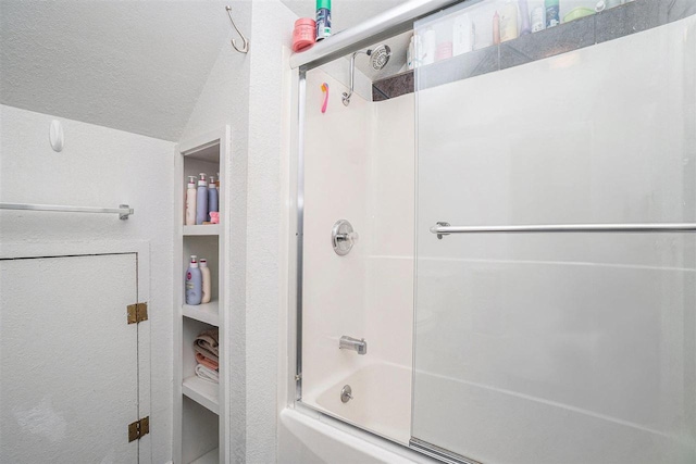 bathroom featuring bath / shower combo with glass door, a textured ceiling, and vaulted ceiling