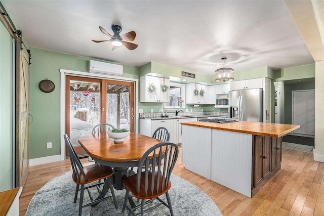 dining space featuring a barn door, sink, french doors, light hardwood / wood-style flooring, and a wall mounted AC