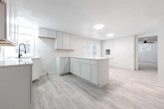 kitchen featuring sink, plenty of natural light, white cabinetry, and brick wall