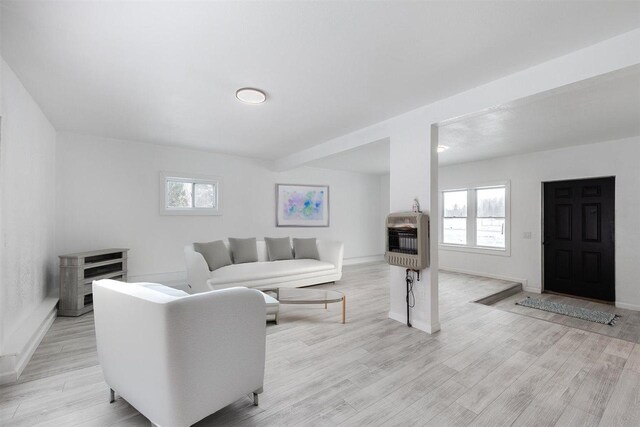 living room with light wood-type flooring, heating unit, and plenty of natural light