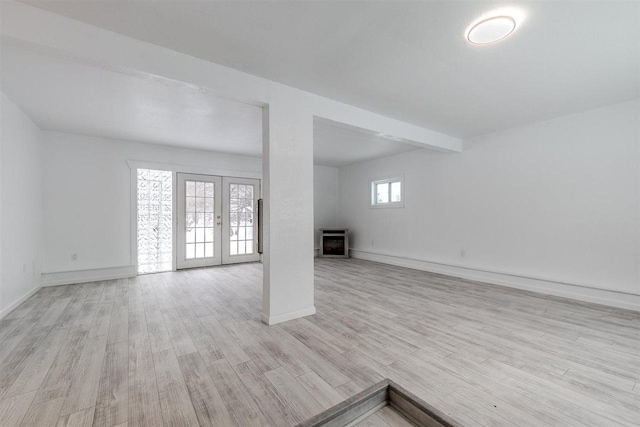 unfurnished living room featuring light wood-type flooring, french doors, and beamed ceiling