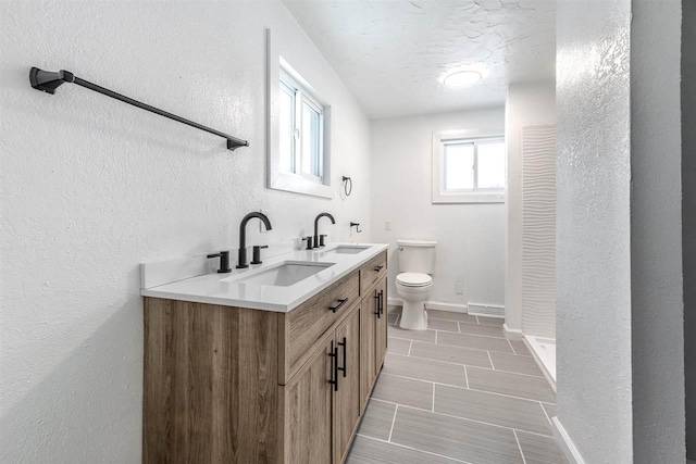 bathroom with vanity, toilet, a shower, and a textured ceiling